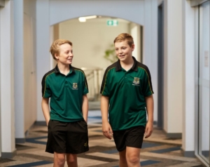 Two junior school boarding student walk down a hall together smiling